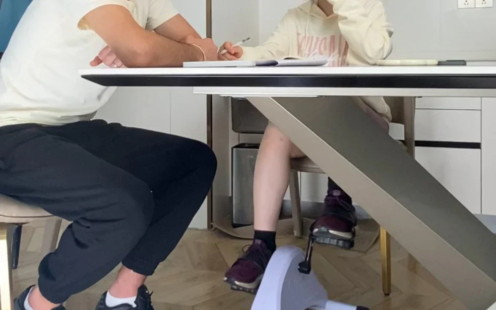 using the Tousains Mini Electric Exercise Bike while talking with colleagues